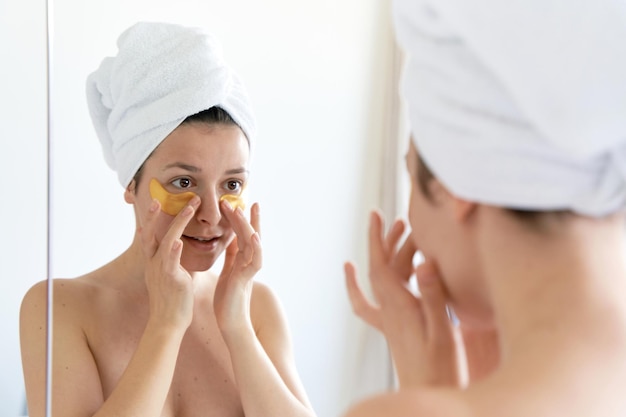 Na het douchen wordt het meisje in een handdoek gewikkeld en draagt ze cosmetische pleisters voor de huid onder de ogen cosmetische ingrepen thuis