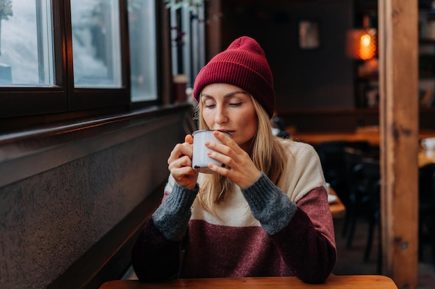 Na het skiën zit een vrouw in een koffie in een gezellige bar en drinkt koffie.