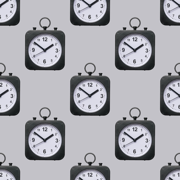 Naadloos patroon van klassieke horloges met handen op een grijze achtergrond.