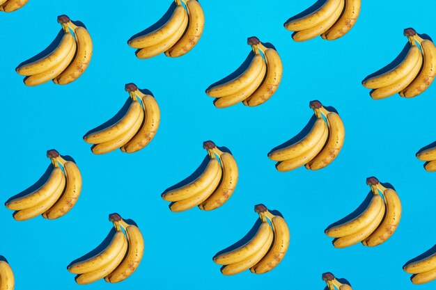 Naadloze lichtblauwe achtergrond met rijp geel bananenpatroon en harde donkere schaduwen. Nieuwe kleurentrend 2021. Minimal scene concept. Tropisch abstract popart fruit afbeelding. Gratis exemplaar ruimte.