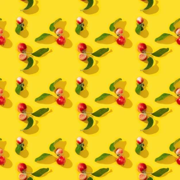 Naadloze patroon van kleine rode appels en groene bladeren op geel