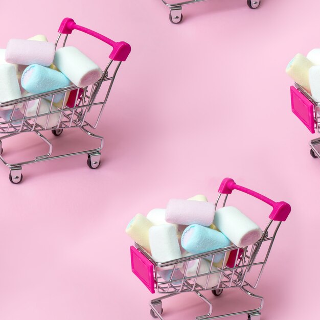 Naadloze patroon veelkleurige marshmallow in mini-winkelwagentje. Winkelen, verkoop en marketing