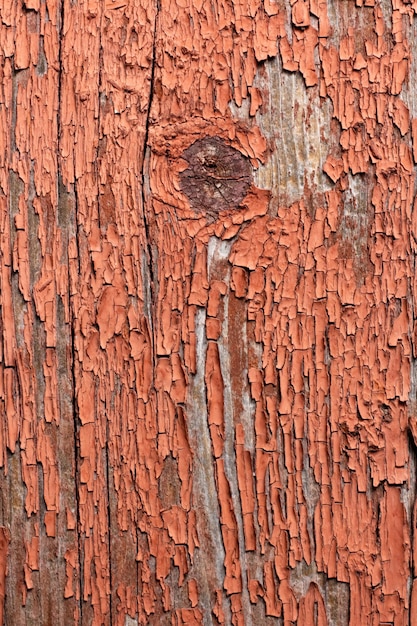 Naadloze textuur van oud hout met scheuren en bleke rode verf. Resten van oude verf op het geverfde houten oppervlak.