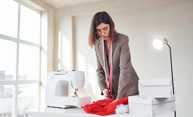 Naaister aan het werk op kantoor Jonge vrouw in formele kleding is binnenshuis Conceptie van stijl