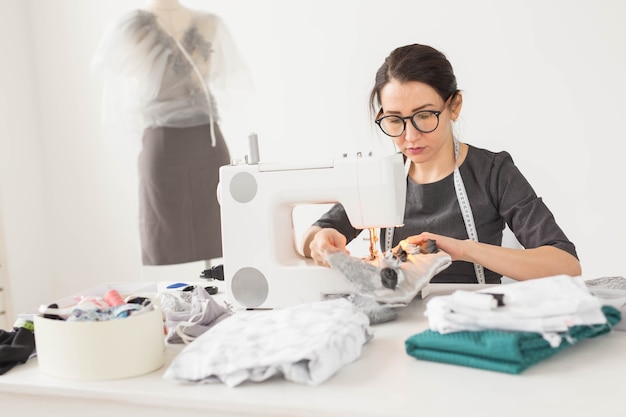 Naaister, kleermaker en creatief concept - portret van modeontwerper met naaimachine op witte achtergrond