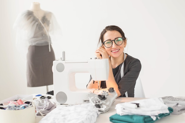 Naaister, kleermaker en creatief concept - portret van modeontwerper met naaimachine op witte achtergrond