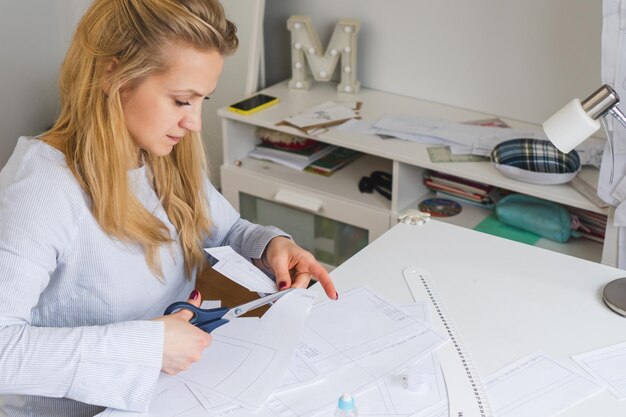 Naaister knipt papieren patronen voor jurk met een schaar Ontwerpontwikkeling en kleding maken