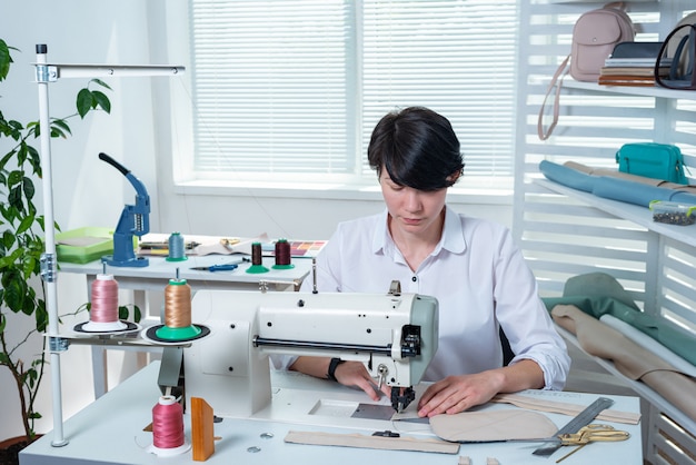 Naaister meisje is op de werkplek achter de naaimachine