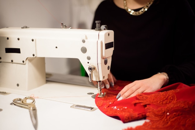 Naaister werkt aan de naaimachine. Op maat maken van een kledingstuk. Hobbynaaien als klein bedrijfsconcept.