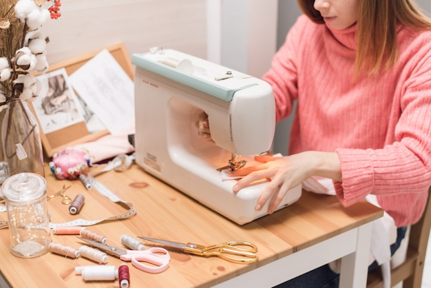 Naaister werkt op een naaimachine. De vrouw naait en houdt een roze doek vast