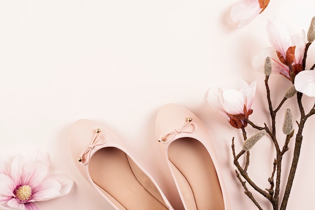 Naakt gekleurde ballerina schoenen en magnolia bloemen.