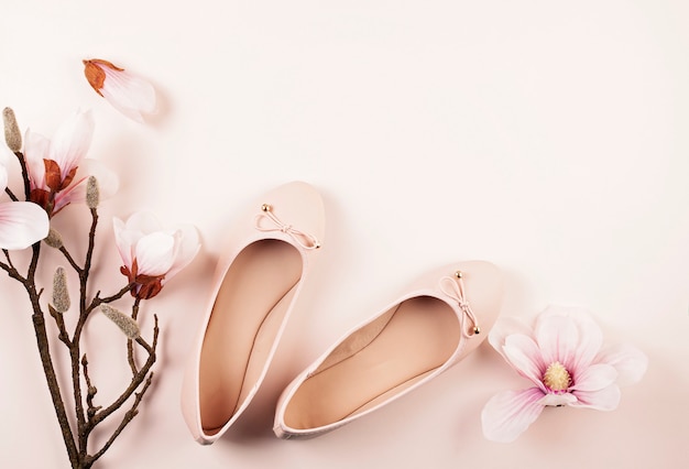 Naakt gekleurde ballerina schoenen en magnolia bloemen.