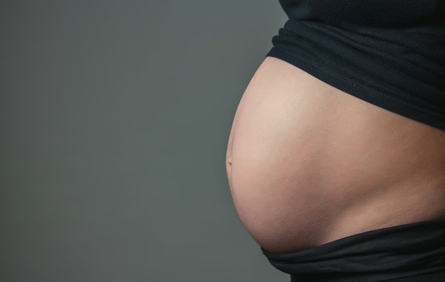 Naakte buik van zwangere vrouw in profiel indoor