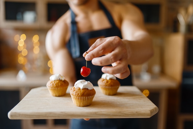 Naakte man in schort dessert op de keuken koken