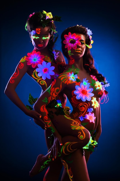 Naakte vrouwen met gloeiende uv body art en bloemen