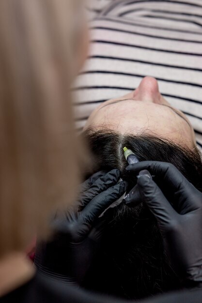 Naald mesotherapie. schoonheidsspecialist maakt injecties in het hoofd van de vrouw. versterken het haar en hun groei.