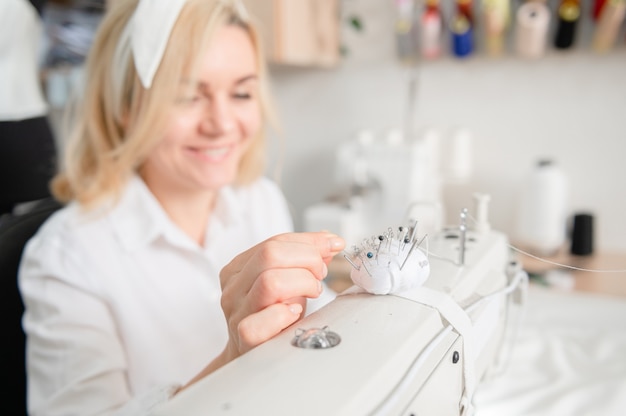 Naalden in een kussen op een naaimachine Werkplek van een naaister Naaiconcept Naaisterwerk