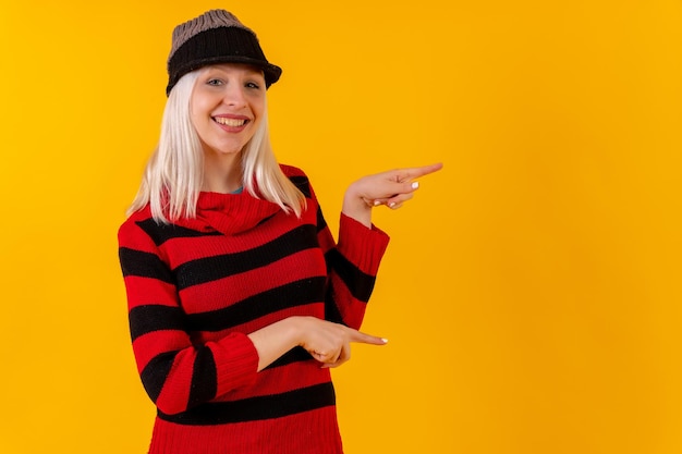 Naar rechts wijzend met kopie ruimte blond blank meisje op gele studio achtergrond