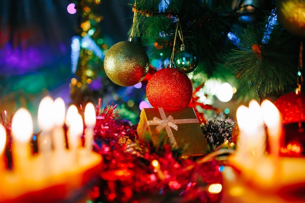 Naast de geschenkdoos hangen kerstversieringen in verschillende kleuren met glitters