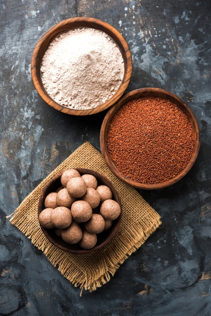 Nachni laddu of Ragi laddoo of balletjes gemaakt van vingergierst, suiker en ghee. Het is een gezond voedsel uit India. Geserveerd in een kom of bord met rauw geheel en poeder. Selectieve focus