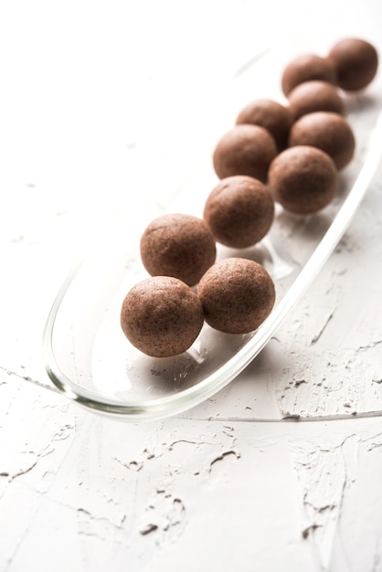 Nachni laddu or Ragi laddoo or balls made using  finger millet, sugar and ghee. It's a healthy food from India. Served in a bowl or plate with raw whole and powder. Selective focus