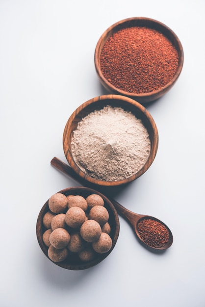 Nachni laddu 또는 Ragi laddoo 또는 손가락 기장, 설탕 및 버터 기름을 사용하여 만든 공. 인도에서 온 건강식입니다. 원시 전체 및 분말과 함께 그릇이나 접시에 제공됩니다. 선택적 초점