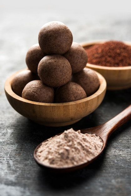 NachniladduまたはRagiladdoo、またはシコクビエ、砂糖、ギーを使用して作られたボール。インドの健康食品です。生の丸ごと粉末を入れたボウルまたはプレートでお召し上がりいただけます。セレクティブフォーカス