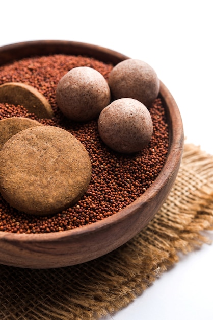 Nachni of Ragi laddu en koekjes of koekjes gemaakt met vingergierst, suiker en ghee. Het is een gezond voedsel uit India. Geserveerd in een kom of bord met rauw geheel en poeder