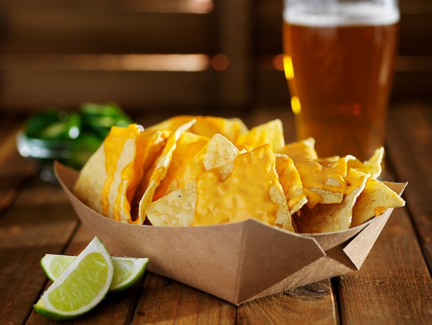 Nachos and cheese in tray with beer