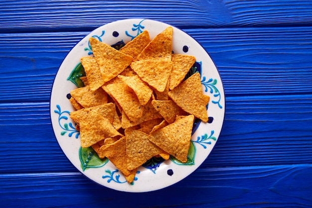 Nachos chips on mexican plate over blue