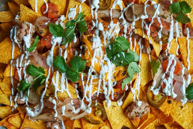 Nachos - a classic mexican appetizer made from corn tortilla chips. nachos with sauces and holopenya. top view. close up