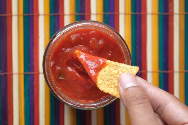 Foto nachos che si tuffano in una salsa al peperoncino