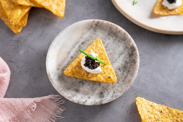 Foto nachos met sturgeon zwarte kaviaar op zure room op een bord