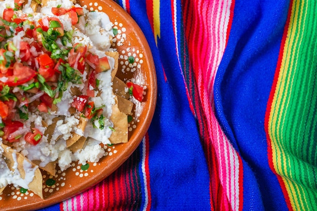 Nachos with cream cheese and pico de gallo on a colorful serape