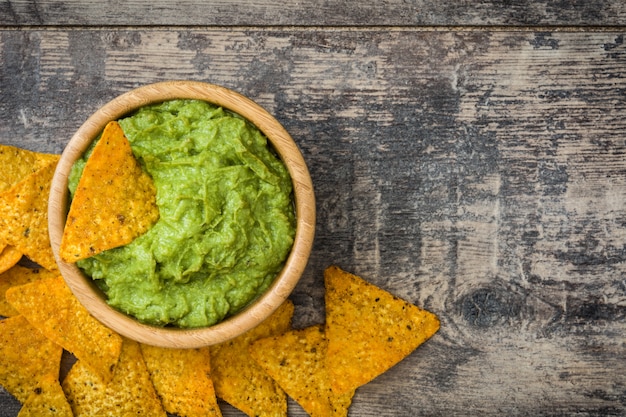 Photo nachos with guacamole on wooden table top view, copy space