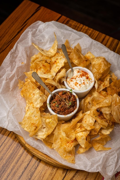 Nachos with sauces on plates on a wooden table