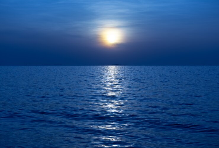 Nacht blauwe kalme zee onder volle maan glans reflecteren op het water oppervlak