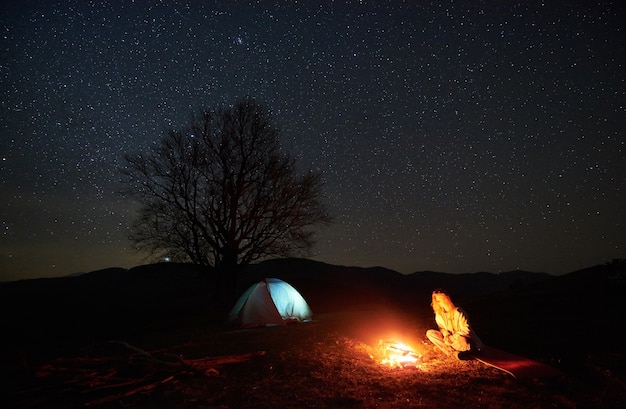 Nacht kamperen. Wandelaar rusten in de buurt van kampvuur onder de sterrenhemel
