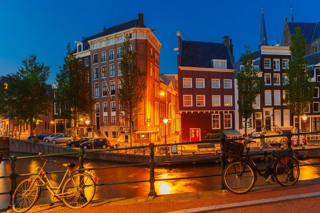 Nacht uitzicht op de stad van Amsterdamse gracht, brug, typische huizen en fietsen, Holland, Nederland.