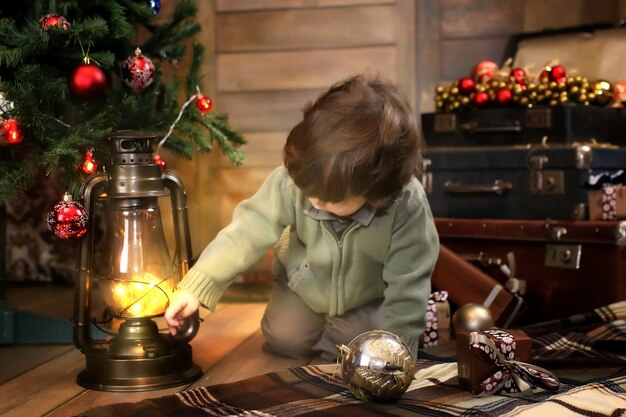 Nacht voor Kerstmis kleine baby zittend op de grond en spelend met speelgoed