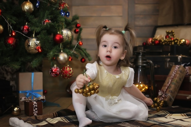 Nacht voor Kerstmis kleine baby zittend op de grond en spelend met speelgoed