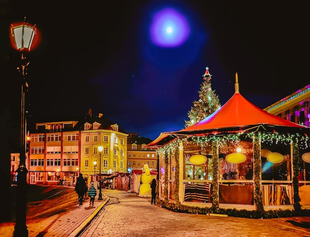 Nachtkerstmarkt op Dome Square met Xmas kraampjes in Riga in Letland Winter. Laat op de avond. Straat- en vakantiebeurs in de Europese stad Adventdecoratie met ambachtelijke artikelen op de Bazaar