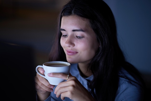 Nachtkoffie en zakenvrouw op kantoor voor het plannen van overuren en ontwerperdeadline Gelukkige glimlach en thee met workaholic van werknemers voor netwerkinnovatie en ontwikkeling in het bedrijf