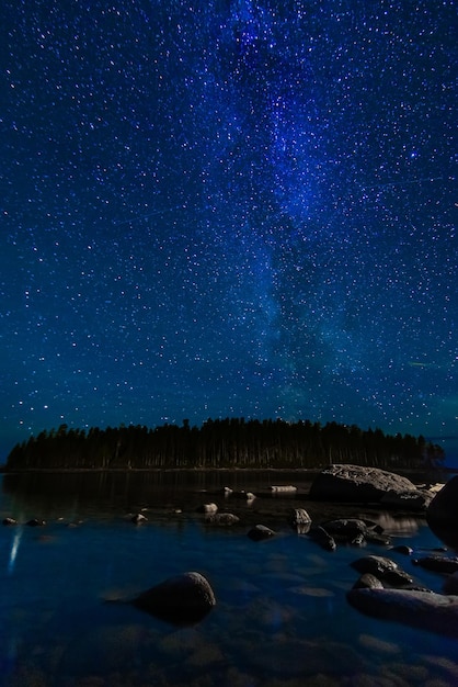 Nachtlandschap met een sterrenhemel en Melkweg met veel heldere sterren Astrofotografie met sterrenbeelden en sterrenstelsels boven water