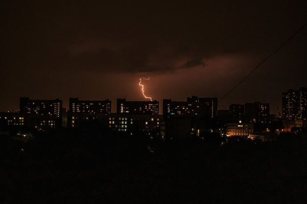 Nachtlandschap van grote stad met gebouwen en bliksem in de wolken Stormweer