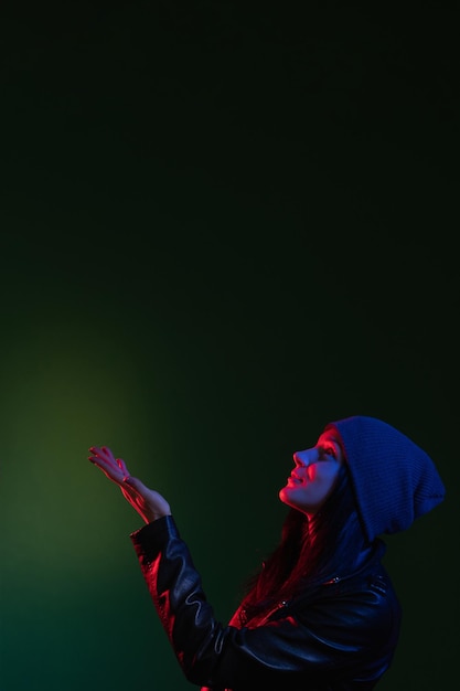 Nachtportret neonlicht geloof hoop geïnspireerde vrouw in hoed rood blauwe gloed die hand opsteekt en omhoog kijkt