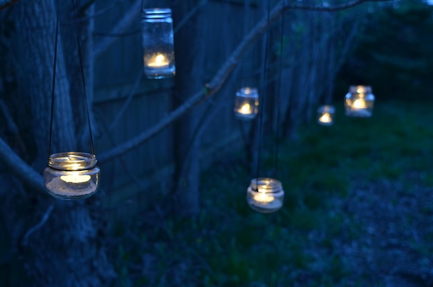 Foto nachttuin handgemaakte lantaarns glazen potten vastgebonden aan boomtaken met thee licht kaars binnen