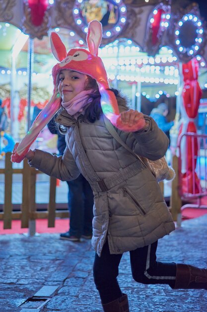 Nachtzicht van een lachend meisje met een roze hoed met verlichte oren met Kerstmis in Toledo, Spanje