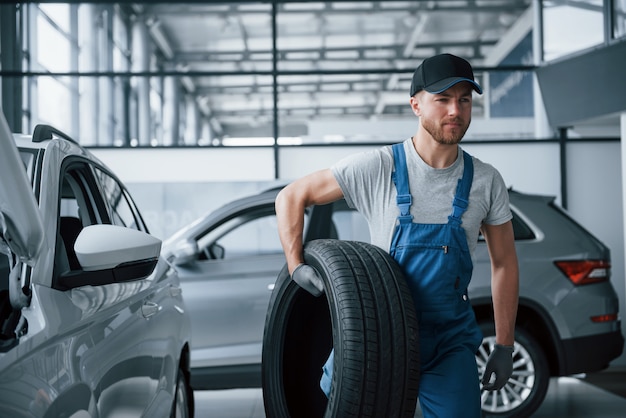 Nadenken over wat te doen. Monteur met een band bij de reparatiegarage. Vervanging van winter- en zomerbanden