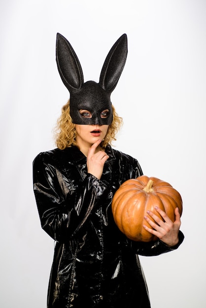 Nadenkend jong meisje in zwart halloween-kostuum serieuze vrouw in konijnenmasker met pompoen sexy meisje